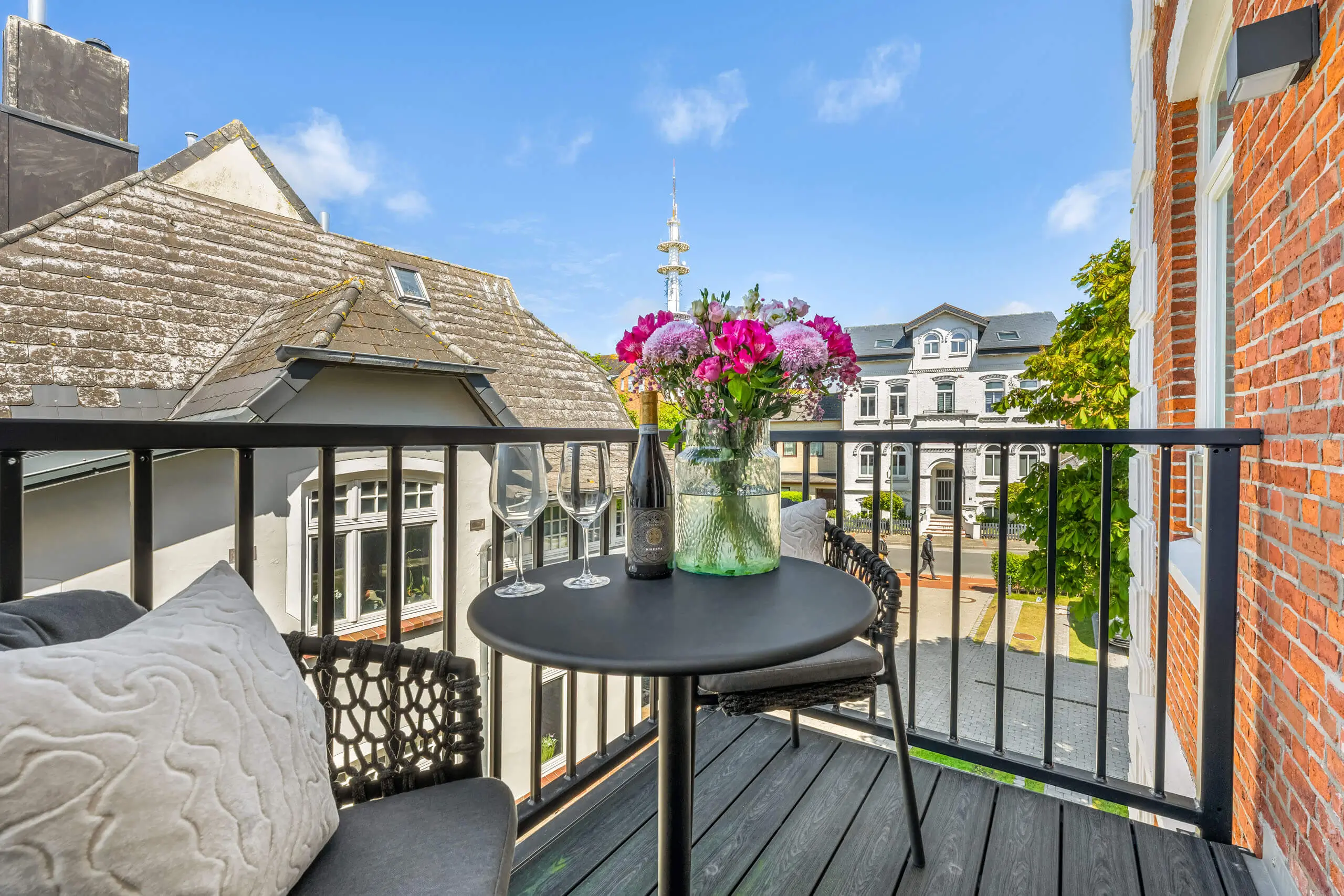 Blick auf den Balkon mit Tisch, Blumen und angrenzendem Gebäude in Westerland, Sylt.