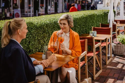 Zwei Frauen genießen Drinks in einem Straßencafé in Westerland, Sylt.