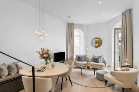 Elegantes Hotelzimmer mit Stühlen, Sofa und Blumenstrauß für einen stilvollen Aufenthalt.