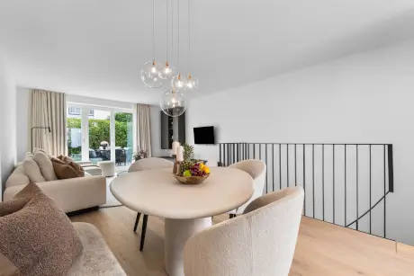 Moderne Hotel-Suite mit Essbereich, runden Tisch und gemütlichem Sofa.