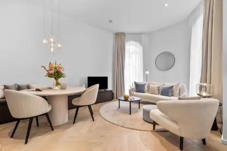 Modernes Hotel-Wohnzimmer mit stilvollem Sofa, Esstisch und zeitgenössischer Ausstattung.