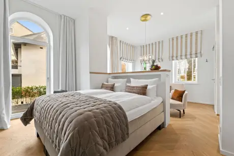 Gemütliches Hotelzimmer mit Bett, Sessel und viel natürlichem Licht.
