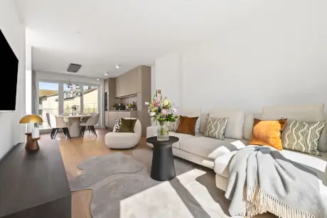 Modernes Hotelzimmer mit einer bequemen Couch, Couchtisch und buntem Blumenstrauß.