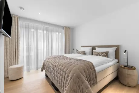 Modernes Hotelzimmer mit einem Doppelbett und großen Fenstern für einen entspannenden Aufenthalt.