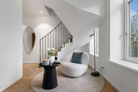 Stylische Hotellobby mit modernem Mobiliar, einschließlich eines Stuhls, Tisches und eleganter Treppe.