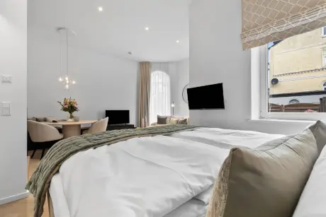 Elegantes Hotelzimmer mit Bett, Essbereich und modernem Fernseher.