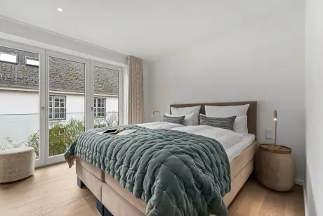 Modernes Hotelzimmer mit bequemen Bett, Nachttisch und großem Fenster.