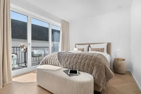 Stylische Hotelzimmer mit einem gemütlichen Bett, Tablet und Balkonblick im 12.18. Hotel Stadt Hamburg, Sylt.