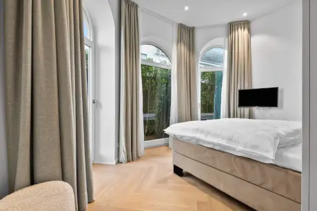 Moderne Hotelzimmer mit Bett, Vorhängen und TV im Hotel Stadt Hamburg.