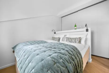 Modernes Hotelzimmer mit stylishen Bett und Wasserflasche auf dem Kopfteil.