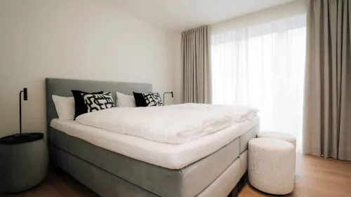 Elegantes Hotelzimmer mit Doppelbett, Kissen und Tageslicht in Sylt.