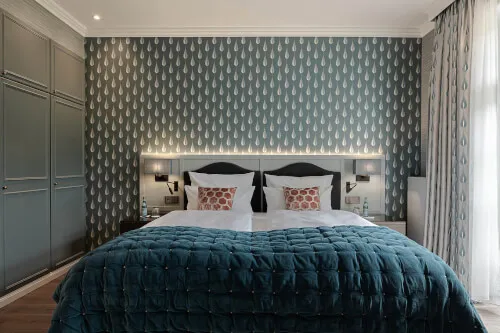 Luxuriöses Bett mit blauer Decke in Suite des 12.18. Hotel Stadt Hamburg, Sylt