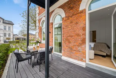 Outdoor-Lounge mit Stühlen und Tisch vor einem eleganten Backsteingebäude im Hotel Stadt Hamburg.