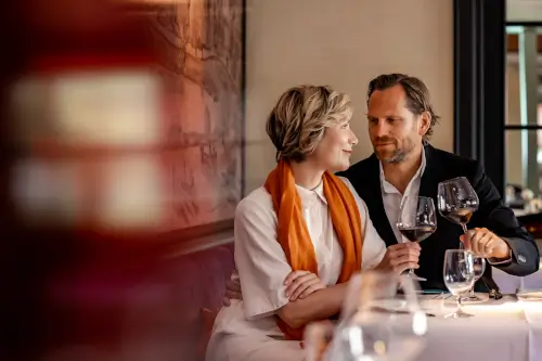 Paar genießt Wein an einem eleganten Tisch im Hotel Stadt Hamburg, Sylt.