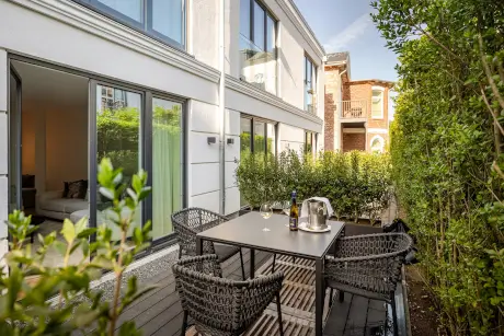 Außenpatio im Hotel Stadt Hamburg mit einem Tisch, Wein und umliegendem Grün.