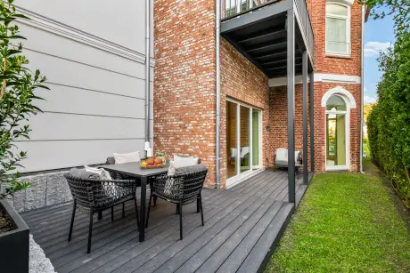 Moderne Terrasse mit gemütlichem Tisch und Stühlen, umgeben von schönen Pflanzen.