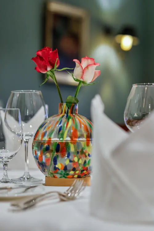 Eine bunte Vase mit Rosen auf einem Esstisch im Hotel Stadt Hamburg.